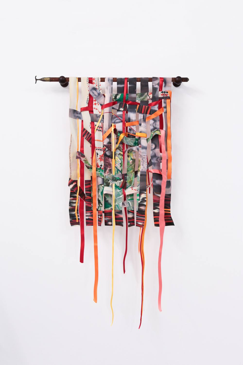 An installation with paintings, textiles and ladders is shown as a physical collage. The space they sit within is white and lit from above.