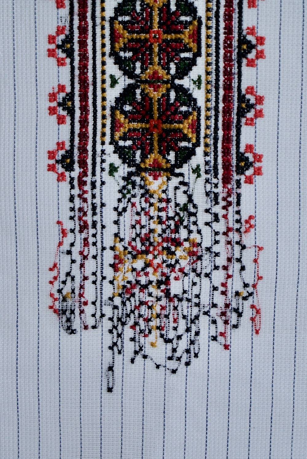 An installation with paintings, textiles and ladders is shown as a physical collage. The space they sit within is white and lit from above.