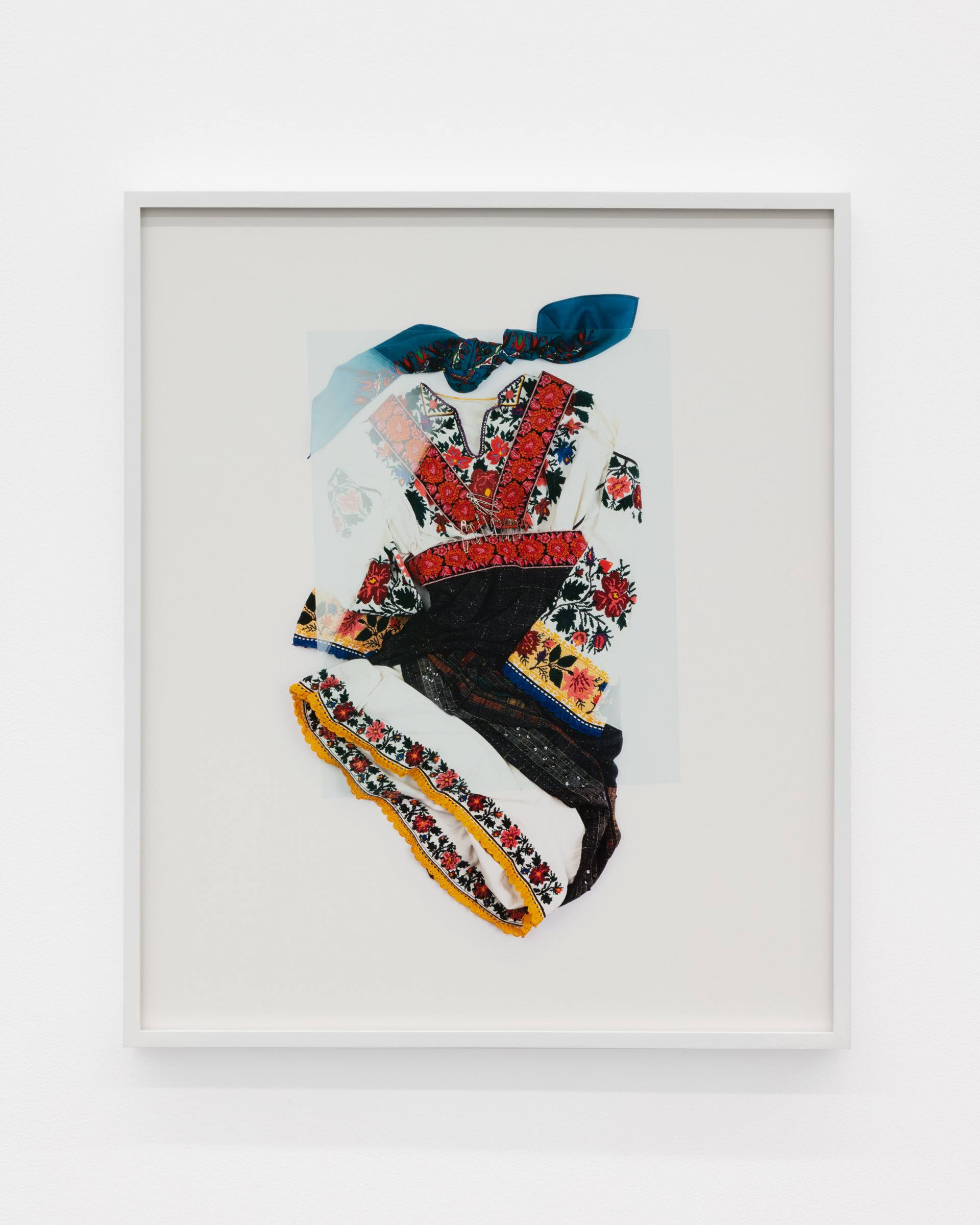 A Carpathian region Ukrainian dance costume is compressed beneath a sheet of glass.